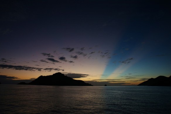 Sunbeams over Monu Island at sunset.